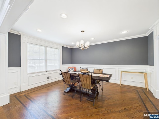 dining room with an inviting chandelier, crown molding, and wainscoting
