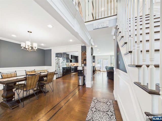 dining room featuring crown molding, wainscoting, an inviting chandelier, recessed lighting, and dark wood-type flooring