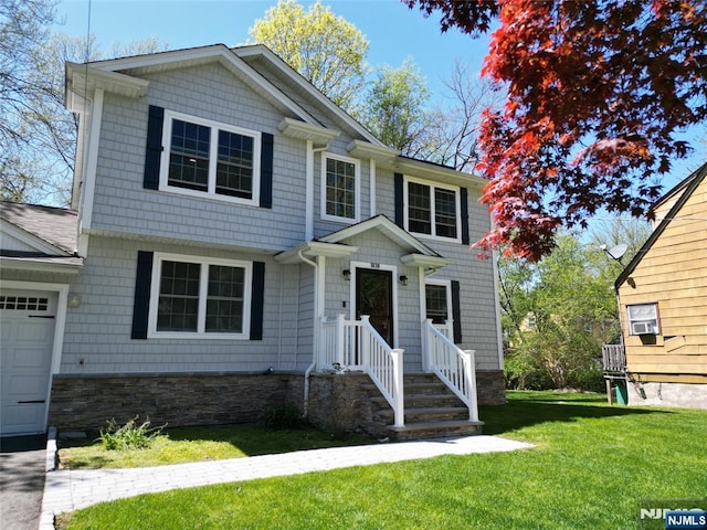 view of front of home featuring stone siding, a front yard, and a garage