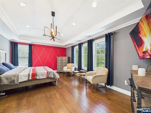 bedroom featuring crown molding, a raised ceiling, wood finished floors, and an accent wall