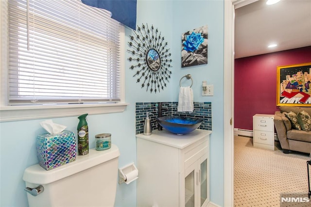 bathroom with decorative backsplash, baseboard heating, vanity, toilet, and recessed lighting