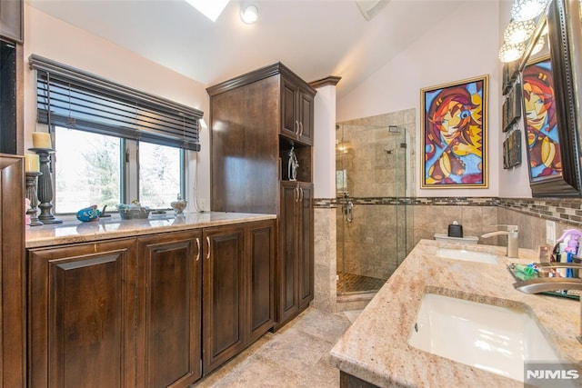 full bath with double vanity, a sink, vaulted ceiling, and a shower stall