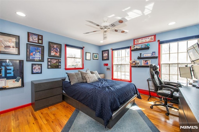 bedroom featuring baseboards, wood finished floors, and multiple windows
