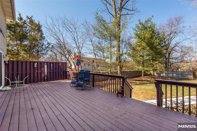 wooden terrace featuring a lawn, a fenced backyard, and a playground