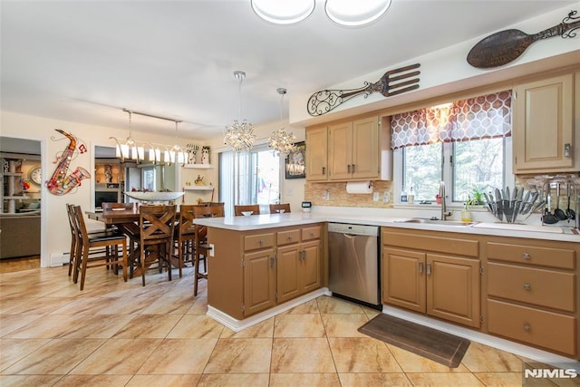 kitchen featuring an inviting chandelier, a sink, dishwasher, light countertops, and a peninsula