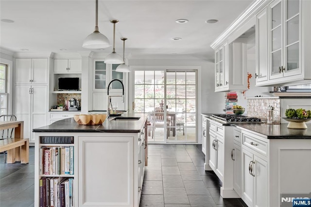 kitchen featuring decorative backsplash, a healthy amount of sunlight, dark countertops, white cabinetry, and a sink