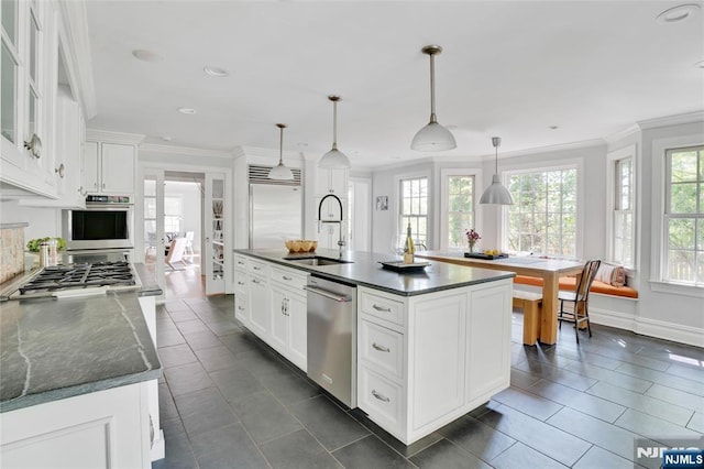 kitchen featuring crown molding, appliances with stainless steel finishes, a sink, white cabinetry, and dark tile patterned flooring