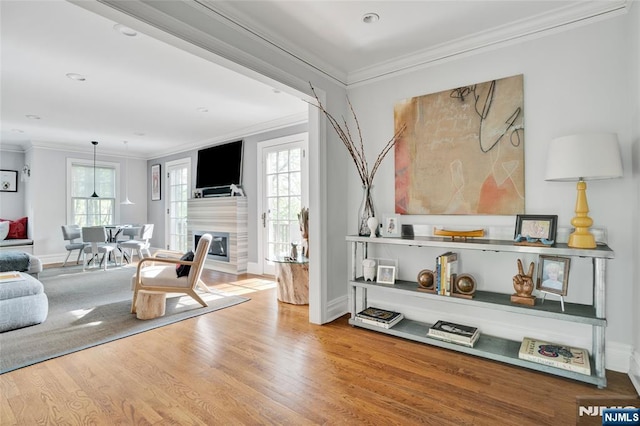 living area with a healthy amount of sunlight, baseboards, ornamental molding, and wood finished floors
