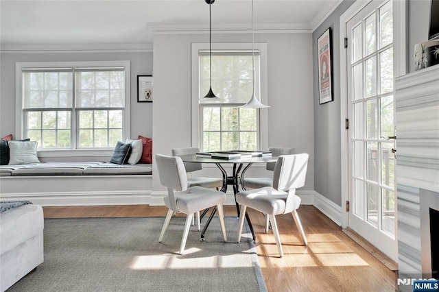 dining room with baseboards, ornamental molding, and light wood finished floors
