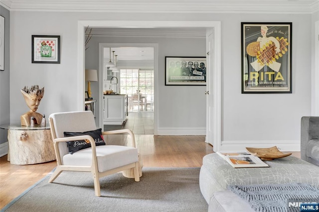 sitting room featuring baseboards, ornamental molding, and wood finished floors