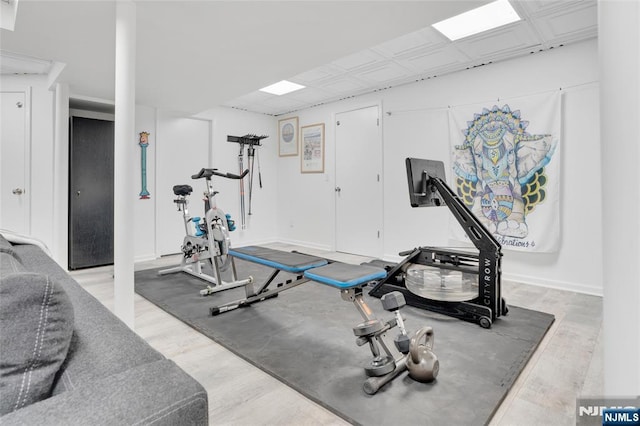 workout room featuring baseboards and light wood finished floors