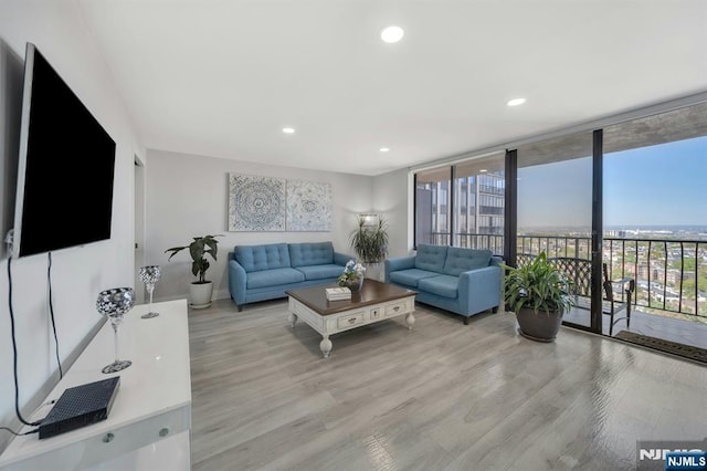 living area featuring baseboards, recessed lighting, expansive windows, and wood finished floors