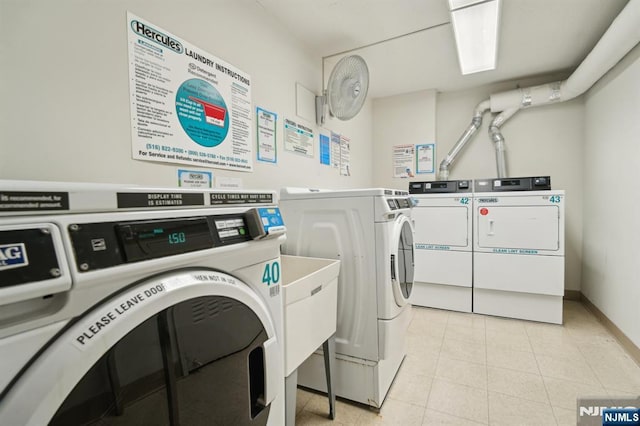 common laundry area with baseboards, washer and clothes dryer, and light tile patterned floors