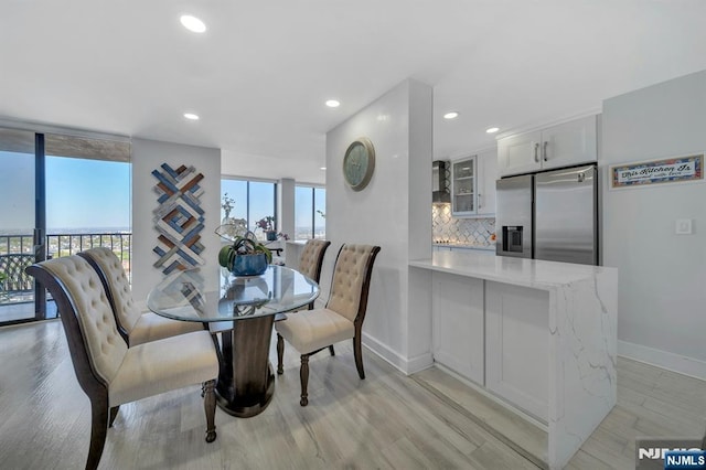 dining space with baseboards, recessed lighting, light wood-style floors, and expansive windows