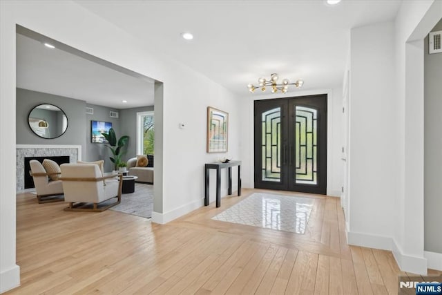 foyer entrance featuring baseboards, a notable chandelier, french doors, and hardwood / wood-style flooring