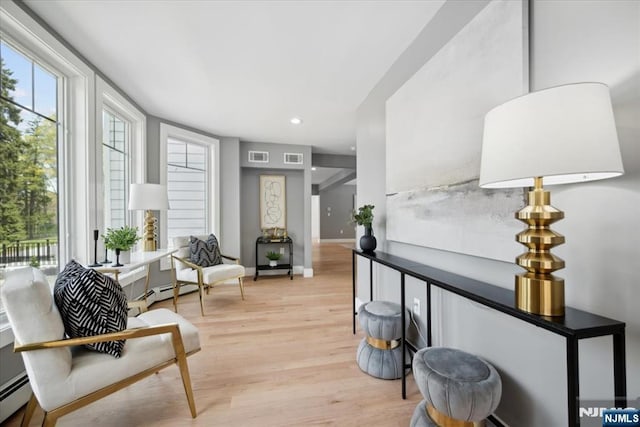 living area with visible vents, baseboard heating, baseboards, light wood finished floors, and recessed lighting