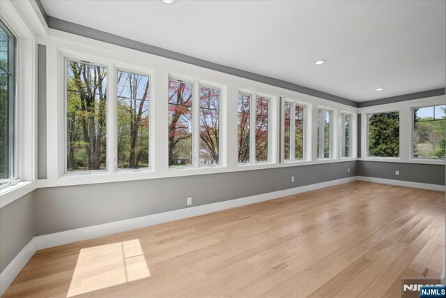 unfurnished sunroom with baseboards, recessed lighting, and wood finished floors