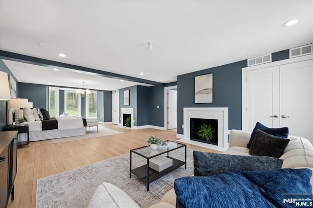 living room featuring visible vents, a fireplace with flush hearth, and recessed lighting