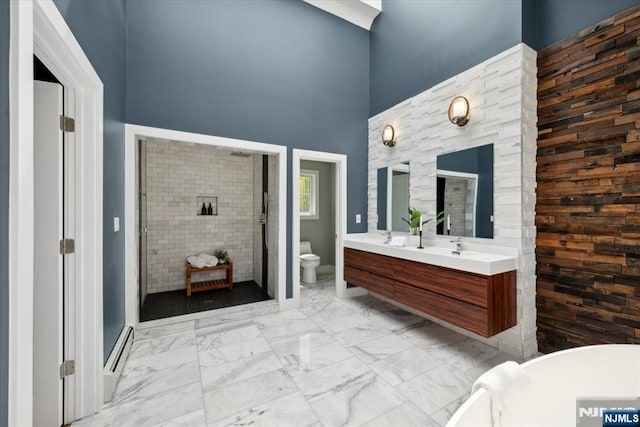 bathroom featuring double vanity, toilet, marble finish floor, a shower stall, and a baseboard radiator