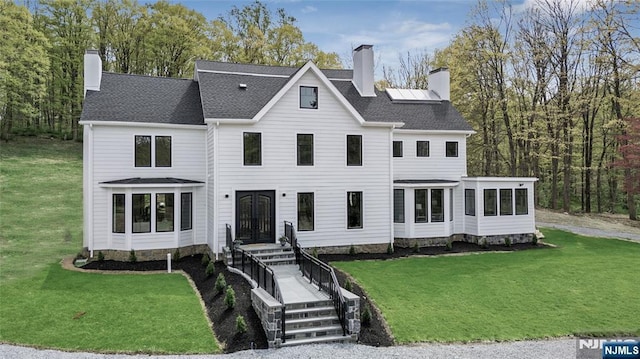 view of front of house featuring a chimney, a sunroom, and a front lawn