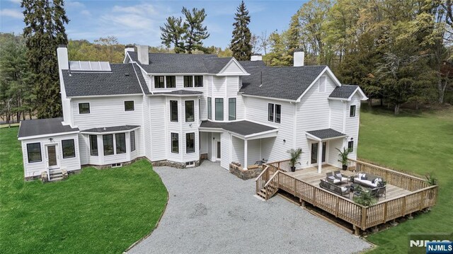 rear view of house with a yard, a deck, driveway, and a chimney