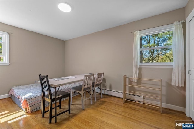 dining area with a healthy amount of sunlight, baseboards, a baseboard heating unit, and wood finished floors