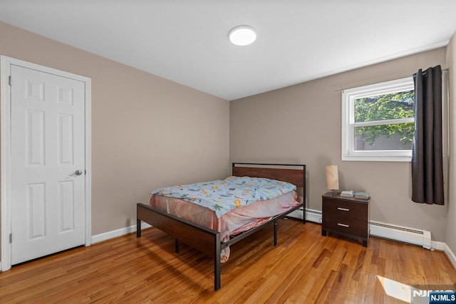 bedroom with baseboards, light wood-style flooring, and baseboard heating