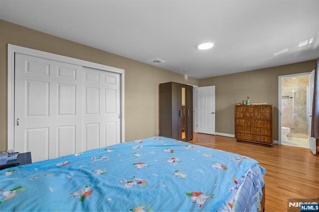 bedroom featuring a closet, baseboards, ensuite bathroom, and wood finished floors