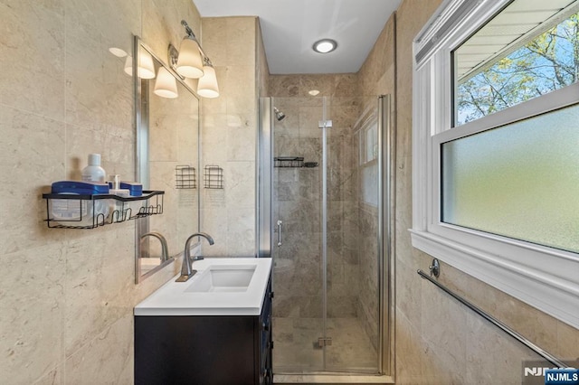 bathroom with vanity, a stall shower, and tile walls