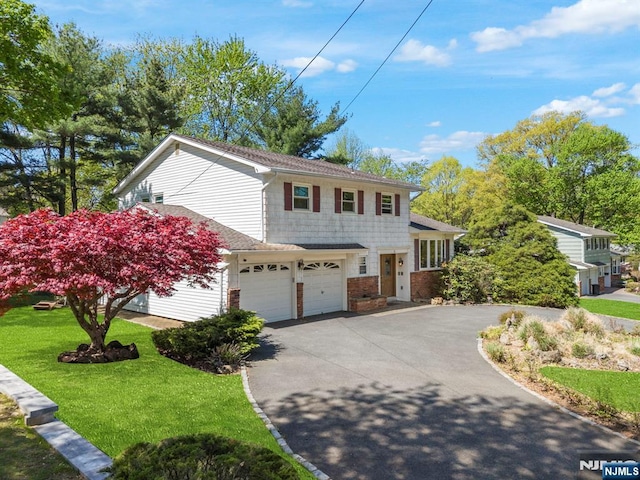 view of front facade with a garage, a front yard, and aphalt driveway