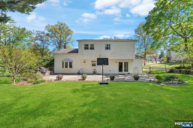 rear view of house with a patio, a lawn, french doors, and a chimney