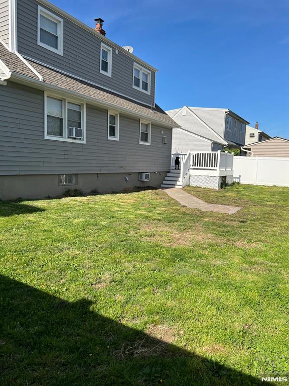 68 Echo Pl, Elmwood Park, NJ 07407 - rear view of house featuring a lawn, a wooden deck, cooling unit, and roof with shingles