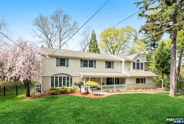 back of property featuring a porch, a lawn, fence, and brick siding