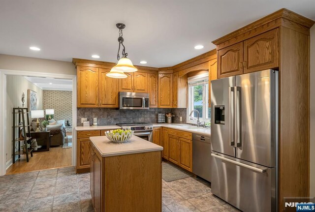 kitchen with light countertops, stainless steel appliances, decorative backsplash, and a sink