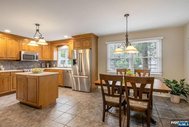 kitchen with light countertops, appliances with stainless steel finishes, a wealth of natural light, and tasteful backsplash