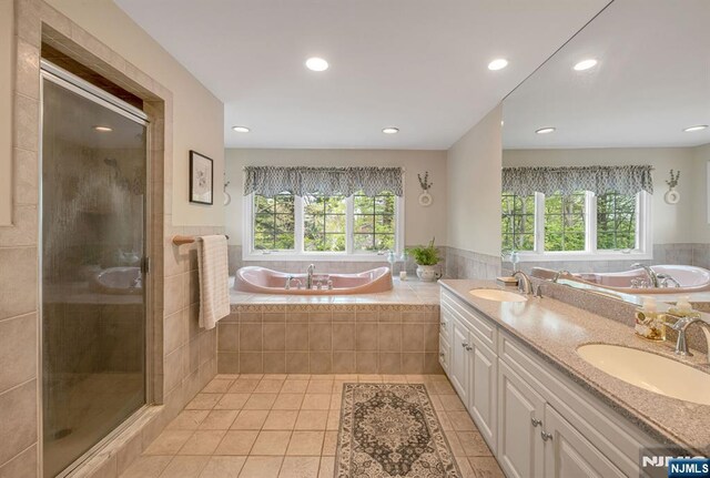 full bath with tile patterned floors, a shower stall, a sink, and a garden tub