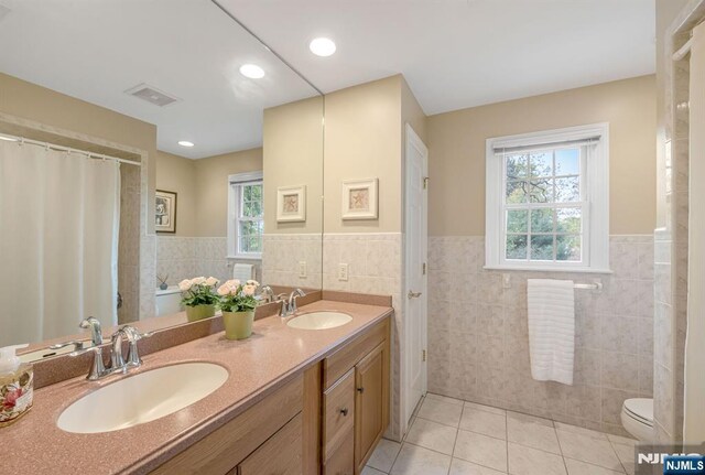 bathroom with visible vents, a sink, tile patterned floors, and tile walls