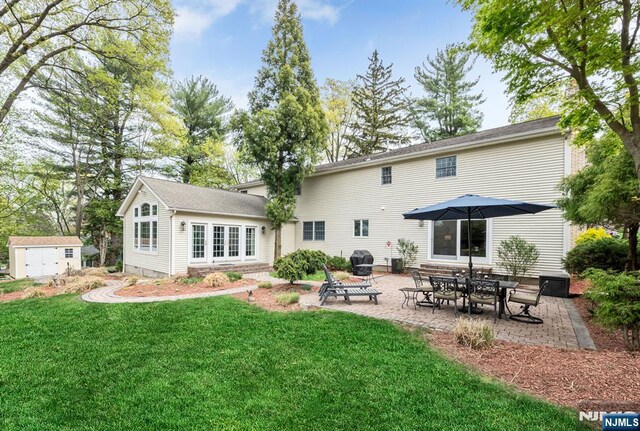 back of house with a lawn, an outbuilding, and a patio area