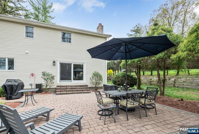 view of patio featuring entry steps, outdoor dining space, and a grill
