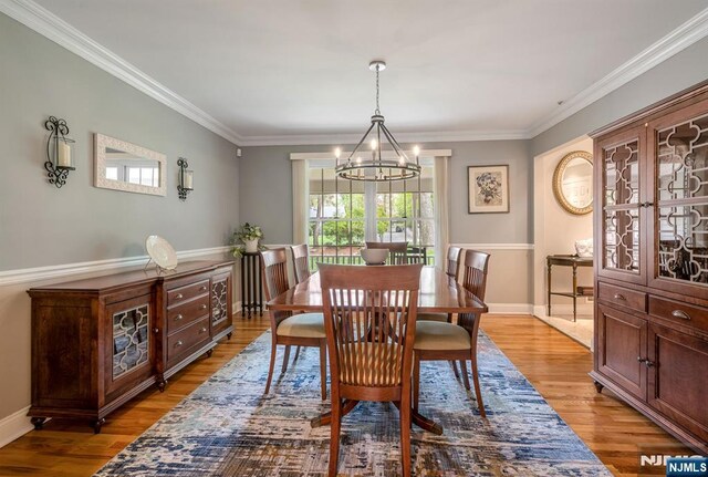 dining area featuring crown molding, baseboards, wood finished floors, and a notable chandelier