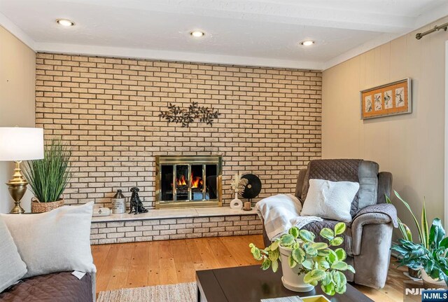 living room with brick wall, hardwood / wood-style flooring, and a fireplace