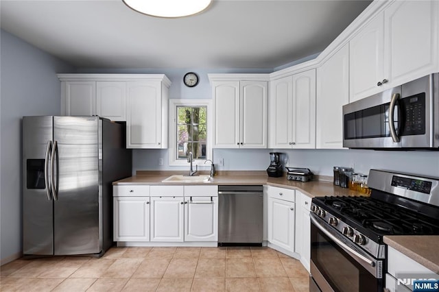 kitchen featuring white cabinets, stainless steel appliances, light tile patterned floors, and a sink