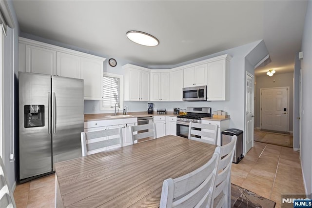 kitchen with light countertops, stainless steel appliances, white cabinetry, and a sink