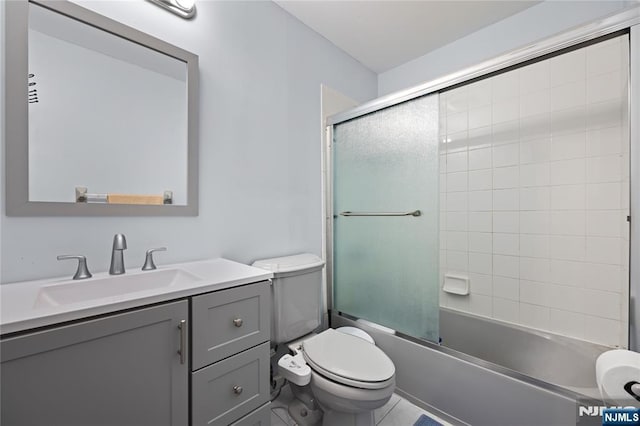 full bathroom featuring vanity, combined bath / shower with glass door, and toilet