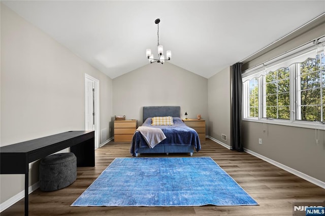 bedroom with baseboards, vaulted ceiling, an inviting chandelier, and wood finished floors