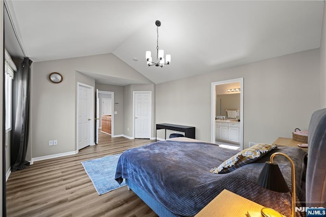 bedroom with a chandelier, baseboards, wood finished floors, lofted ceiling, and ensuite bathroom