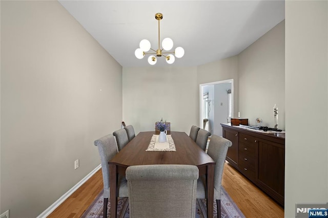 dining room with baseboards, a notable chandelier, and light wood-style flooring
