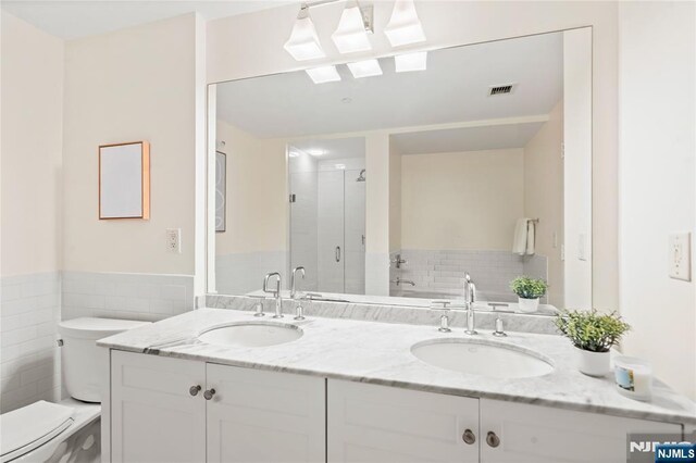 bathroom with visible vents, a sink, toilet, and a shower stall