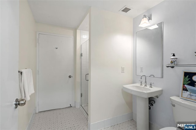 bathroom with toilet, baseboards, visible vents, and a stall shower
