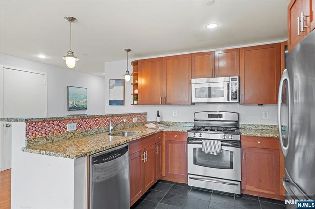 kitchen with a sink, brown cabinets, stainless steel appliances, and a peninsula